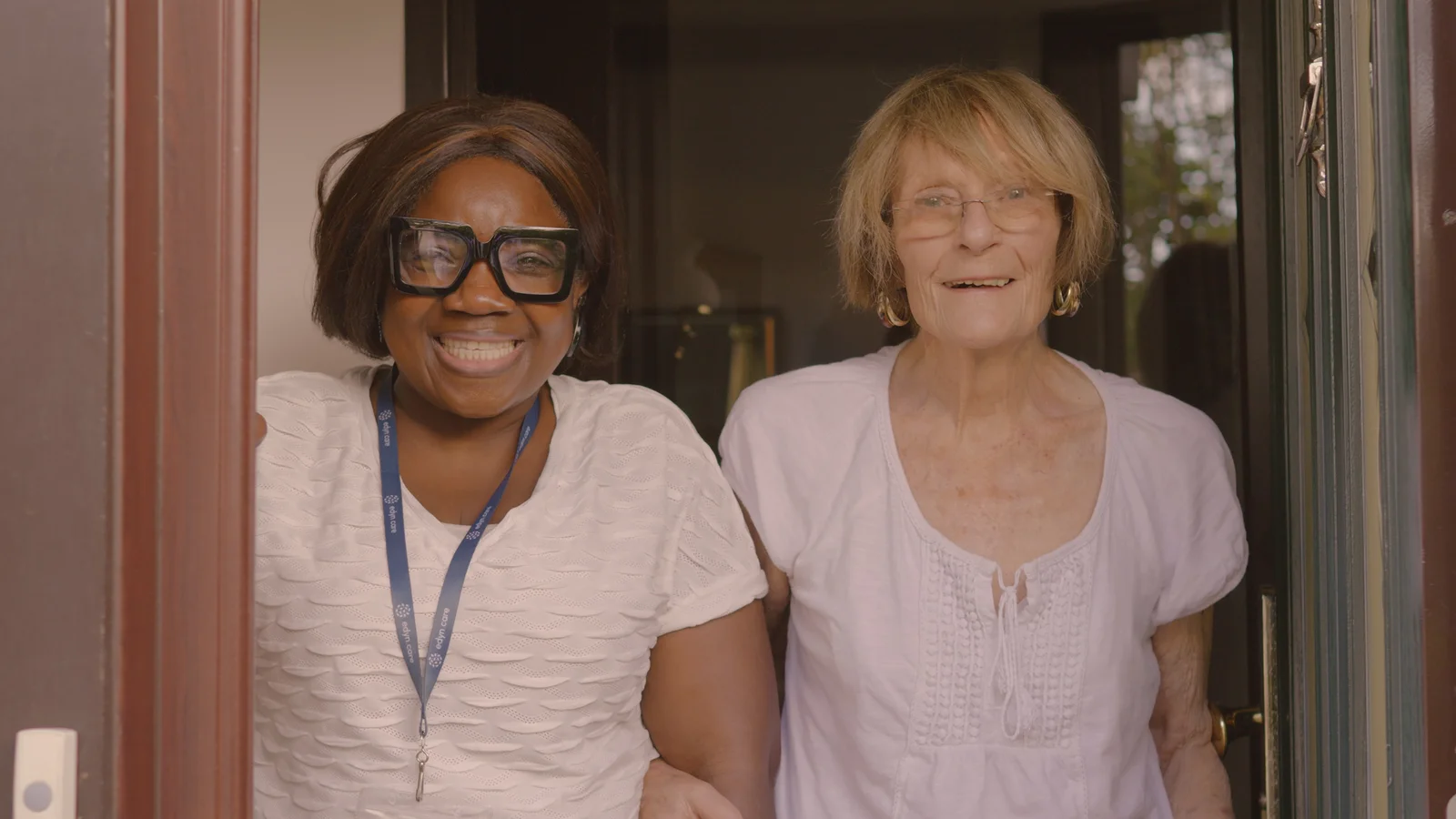 An Edyn carer and an older woman smiling together at her front door